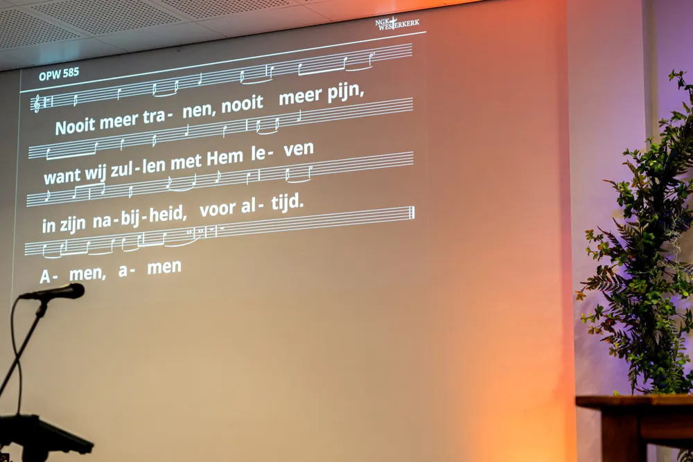 Beamer in de kerkzaal van de Westerkerk met de tekst van Opwekking 585 op het scherm